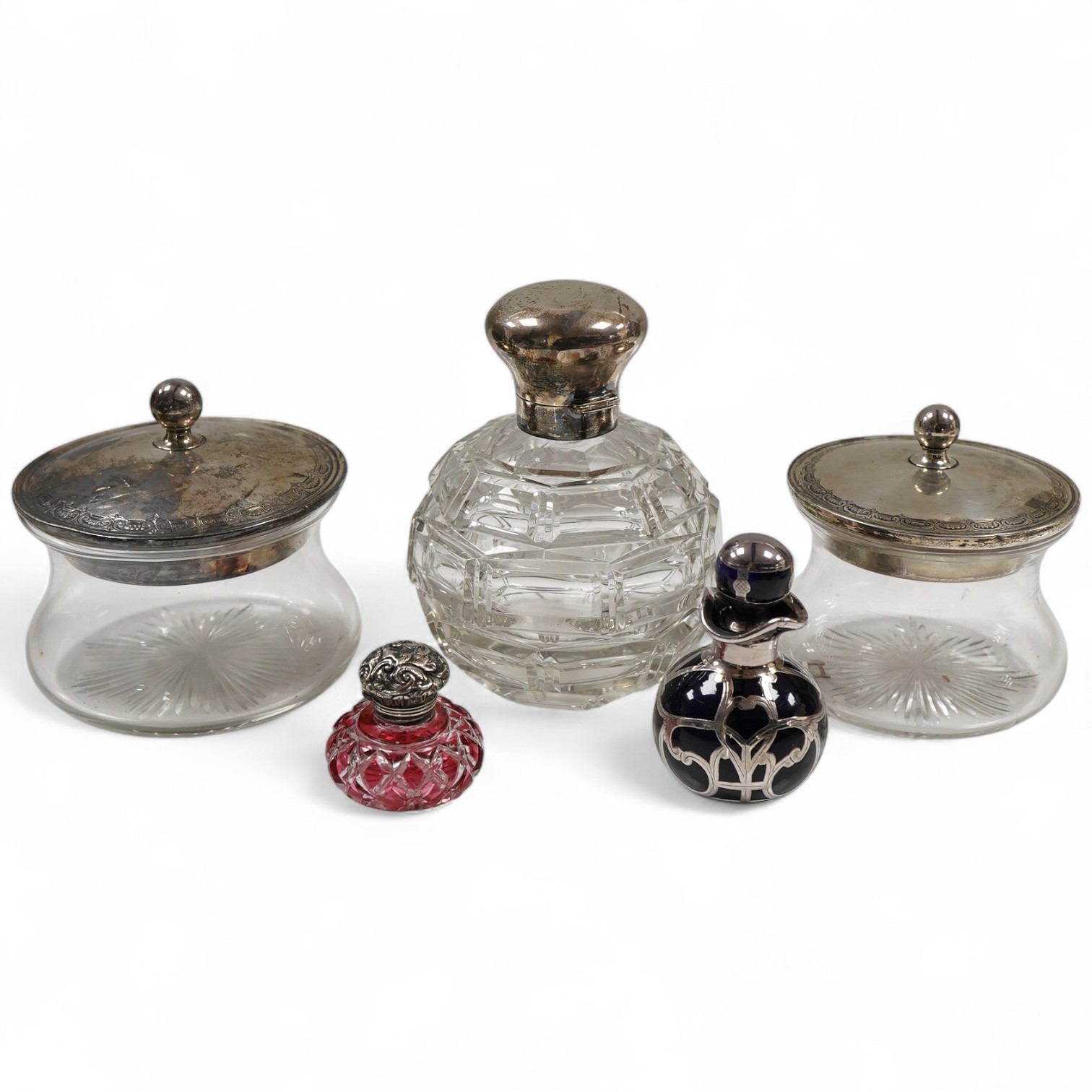Two George V silver mounted glass powder jars, Henry Matthews, Birmingham, 1923, two silver mounted cut glass scent bottles including ruby flash and a white metal overlaid blue glass scent bottle.